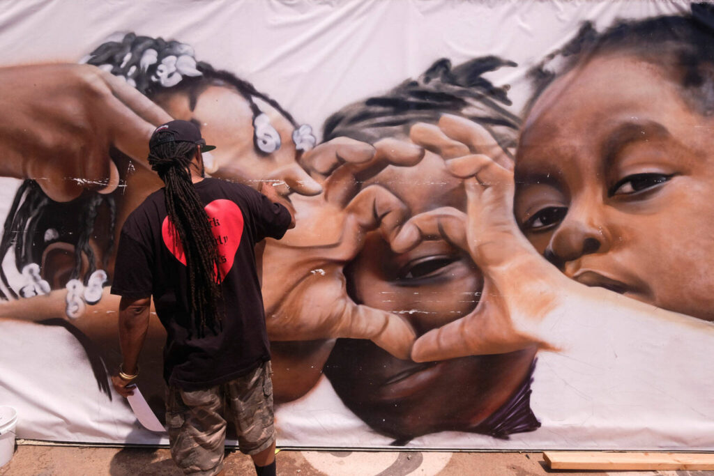 Artist Enkone works on a mural during a Juneteenth commemoration at Leimert Park Plaza on Saturday June 19 2021 in Los Angeles. Ringo H.W. Chiu Associated Press